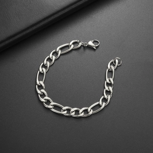 Detailed view of silver Figaro chain link bracelet with lobster clasp on grey surface