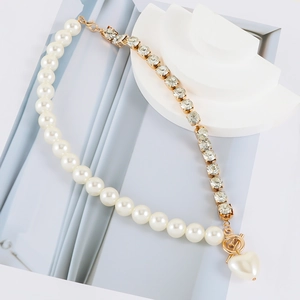 Macro view showing asymmetrical pearl and rhinestone chain with a gold heart pendant
