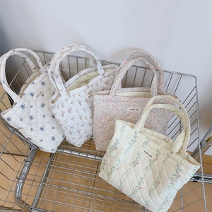 Detailed close-up of four quilted floral cotton handbags with elegant patterns and logo labels