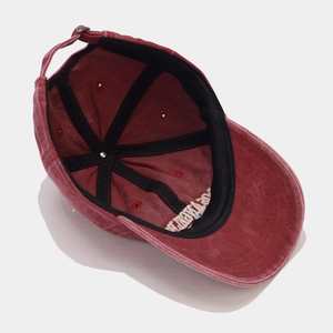 Detail of burgundy washed cotton baseball cap with interior embroidery and adjustable metal buckle