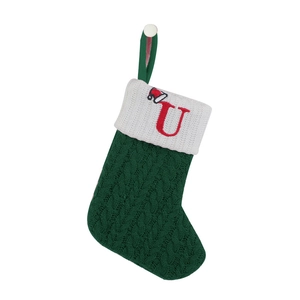 Detail of green knitted Christmas stocking with white cuff and red embroidered letter U
