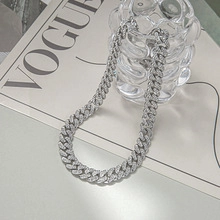 Detailed view of silver Cuban link chain with crystals on a VOGUE magazine backdrop