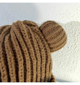 Gros plan du bonnet tricoté marron avec oreilles d'ours montrant la texture épaisse