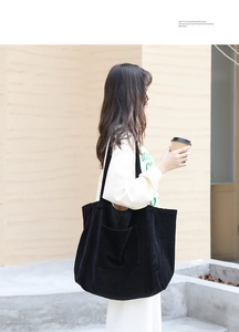 Detail of black corduroy tote bag with large front pocket and wide shoulder strap