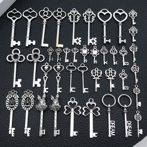 Flat lay of vintage silver alloy key charms in various shapes on a black leather surface