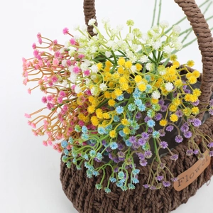 Macro shot of colorful artificial baby breath flowers in a brown woven basket on white