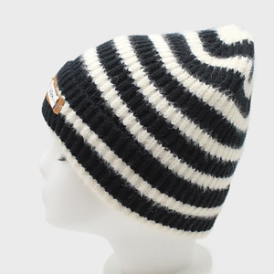 Detail of black and white striped knit beanie with decorative brown leather patch