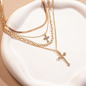 Close-up of gold layered necklace with sparkling cross pendants on a white tray
