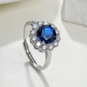 Close-up of a silver halo ring featuring a blue center stone and sparkling accent gems