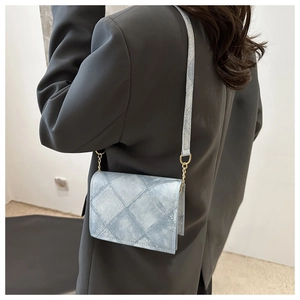 Light blue quilted crossbody bag with golden hardware worn over a grey blazer