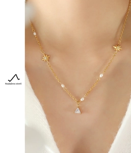 Detail of stainless steel star and pearl necklace with a triangular pendant on a model