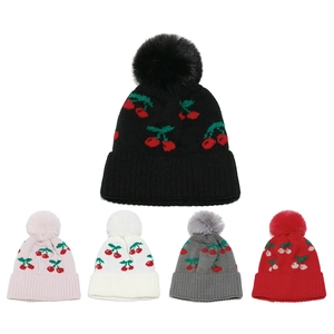 Detailed view of cherry jacquard knit hats with faux fur pom-poms in five colors