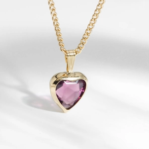 Macro shot of polished gold-tone S925 silver necklace with heart-shaped purple topaz stone