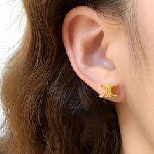 Close-up of golden Triomphe style hoop earring worn on ear with polished finish