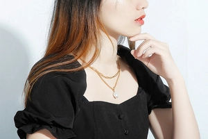 Close-up of double-layered gold necklace with paperclip chain and baroque pearl pendant