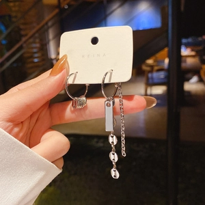 Detail view of asymmetric silver pearl drop earrings with elegant long chain fringe