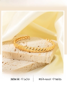 Detail of twisted 18K gold plated stainless steel cuff bracelet on textured stone