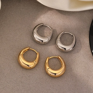 Minimalist U-shaped hoop earrings in polished gold and silver finish on silk background