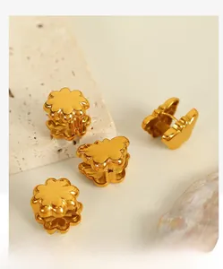 Close-up of gold butterfly and flower huggie earrings on marble and shell background