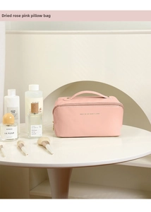Detail of dusty rose pink leather pillow makeup bag with top handle and gold zipper