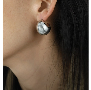 Close-up of polished silver teardrop earrings with high-gloss mirror finish and modern style