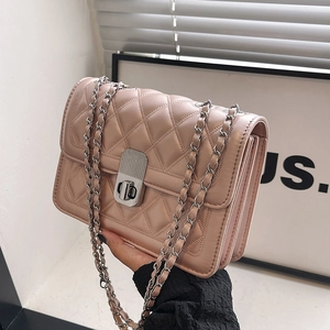 Detail of pink quilted crossbody bag featuring silver chain strap and metal twist lock
