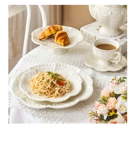 Detail of vintage white embossed ceramic tea set with elegant floral relief on table
