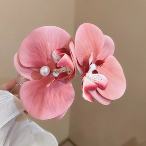 Detailed macro view of pink fabric orchid hair clips featuring decorative center pearls