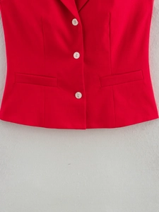 Gros plan du gilet rouge montrant trois boutons blancs et texture de tissu sergé