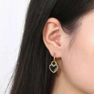 Minimalist heart charm hoop earrings in gold and black enamel, worn on a model