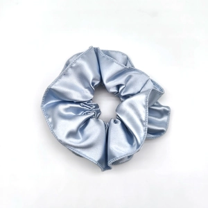 Detailed close-up of a blue satin scrunchie showing glossy texture and fabric folds