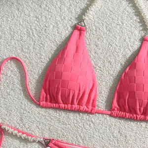 Close-up of pink checkered bikini with white pearl straps on soft plush background