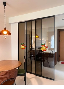 Porte coulissante en verre à cadre noir avec stickers cloches de Noël dans une cuisine