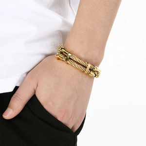 Detailed view of golden double-cable nail bracelet with spikes on male model's wrist