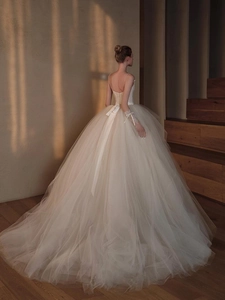 Detailed back view of a lace wedding dress with French train and ribbon bow waist