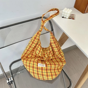 Close-up of yellow and red plaid canvas hobo bag with retro woven label detail