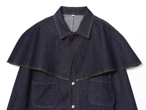 Detail of dark blue denim cape jacket with metal buttons and square pockets