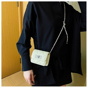 Close-up of beige quilted crossbody bag featuring metal chain strap and square twist lock
