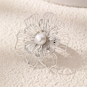 Detailed macro view of an intricate silver hollow flower ring with a central pearl inlay