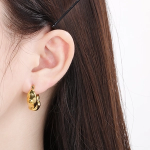 Close-up of golden irregular lava-style earrings with liquid metal texture on ear