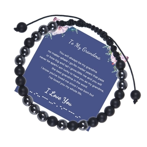 Detail of Morse code bracelet with matte black beads on blue message card