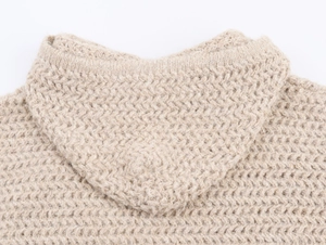 Detailed macro view of the heavy-knit beige hooded neckline with thick textured patterns