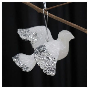 Close-up of a white dove Christmas ornament with silver glitter tips on a branch