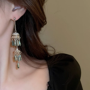 Detailed view of elegant gold tassel earrings with teardrop pearls on a female model