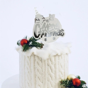 Silver Merry Christmas acrylic cake topper with tree and bell designs on a white cake