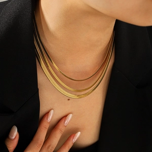 Detailed view of 18k gold triple layered flat snake chains on a model with black suit