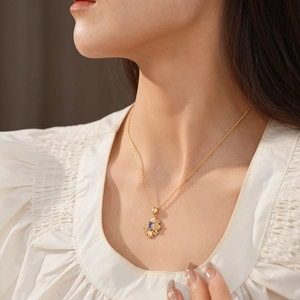 Close-up of vintage gold necklace with sunburst pendant and oval purple gemstone