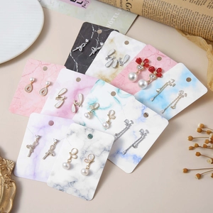 Close-up of marble pattern display cards with elegant pearl and rhinestone earrings
