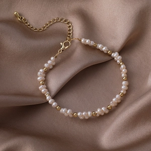 Detailed macro view of white freshwater pearls and golden beads on an adjustable chain