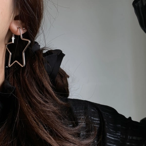 Detailed view of silver minimalist star hoop earrings worn by a model in a close-up shot